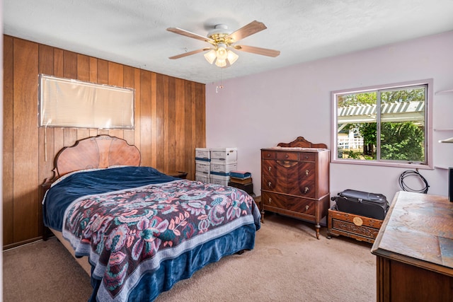 bedroom with ceiling fan, light carpet, and wooden walls