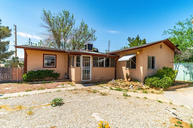 ranch-style home featuring central AC unit, fence, and a sunroom