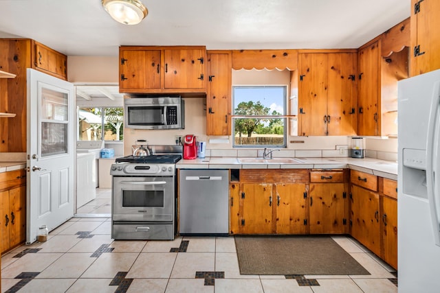 kitchen with brown cabinetry, stainless steel appliances, and plenty of natural light