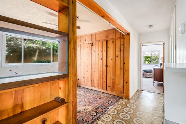 hall featuring wood walls and tile patterned floors