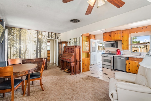 interior space with light carpet, a ceiling fan, and visible vents