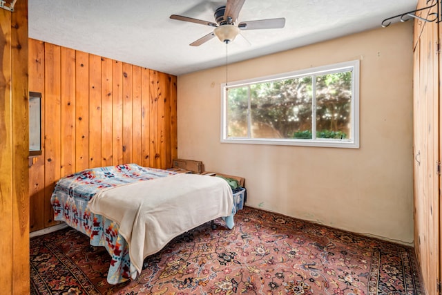 bedroom with wood walls and a ceiling fan