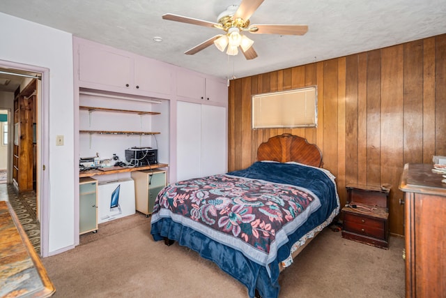 bedroom with light colored carpet, wood walls, and ceiling fan