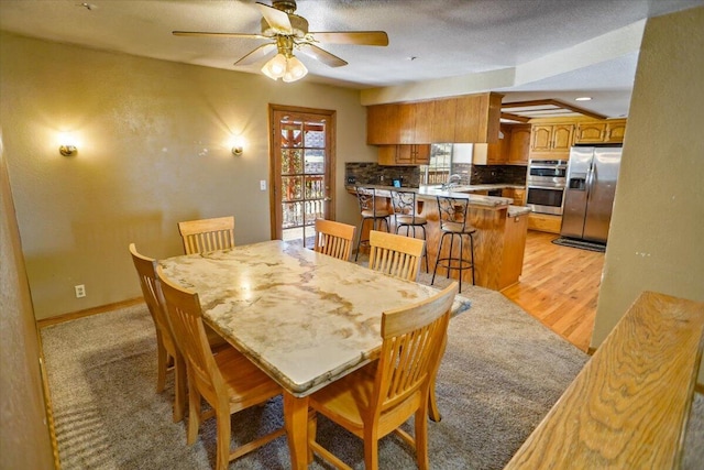 dining room featuring a ceiling fan, light wood-style floors, and baseboards