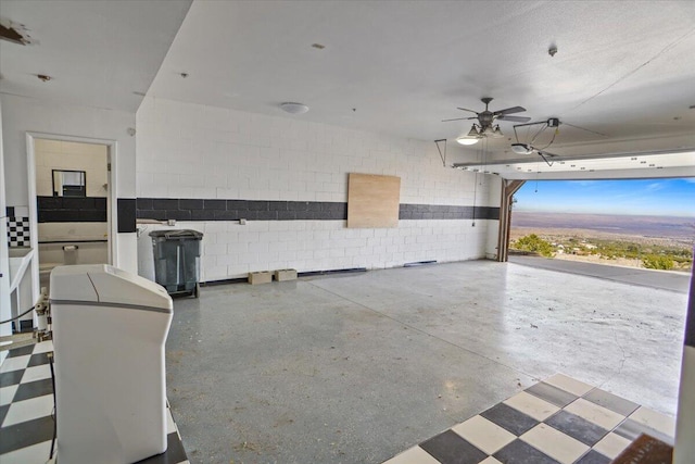 garage featuring concrete block wall and a ceiling fan