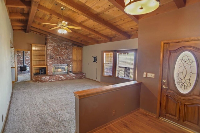 entryway with wood ceiling, vaulted ceiling with beams, a wood stove, and ceiling fan