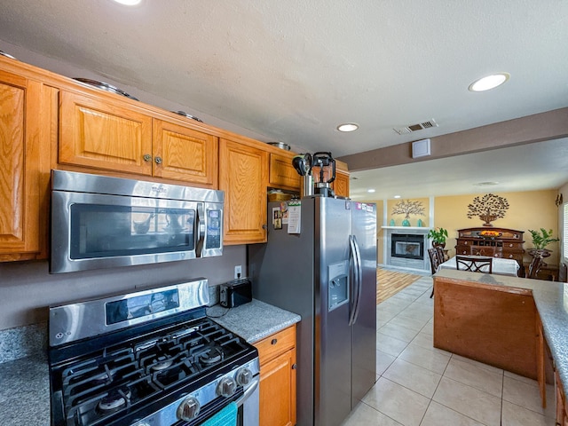 45431 Sancroft Ave, Lancaster, CA 93535 - kitchen with appliances with stainless steel finishes, recessed lighting, open floor plan, light tile patterned floors, and brown cabinets