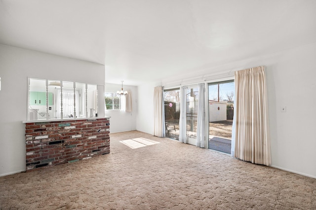 unfurnished living room featuring an inviting chandelier and carpet flooring