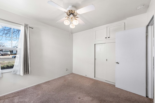 unfurnished bedroom featuring light colored carpet, ceiling fan, a closet, and multiple windows