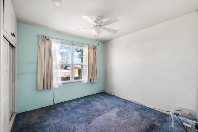 spare room featuring ceiling fan and dark colored carpet