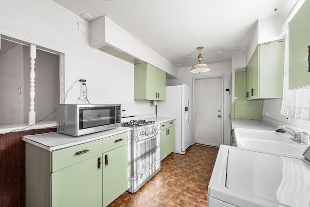 kitchen with white appliances, dark parquet floors, washer / dryer, green cabinets, and sink