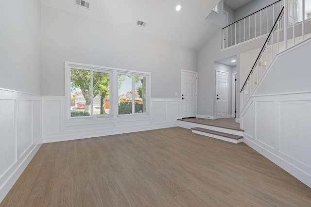 4046 Kona Ct, Palmdale, CA 93552 - unfurnished living room with a decorative wall, high vaulted ceiling, stairway, wood finished floors, and a wainscoted wall