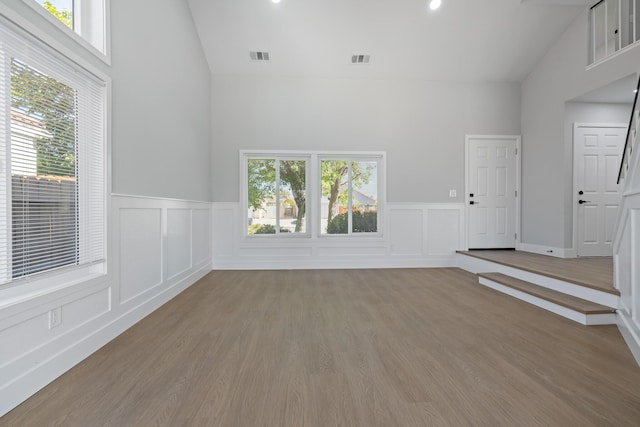 4046 Kona Ct, Palmdale, CA 93552 - unfurnished living room with high vaulted ceiling, healthy amount of natural light, a wainscoted wall, a decorative wall, and wood finished floors