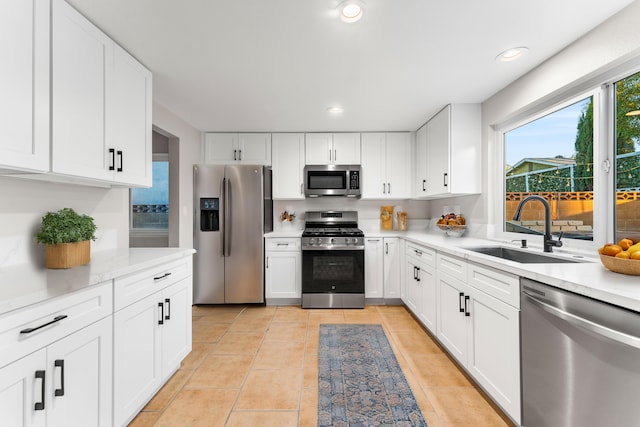 kitchen with white cabinets, light tile patterned floors, stainless steel appliances, and sink