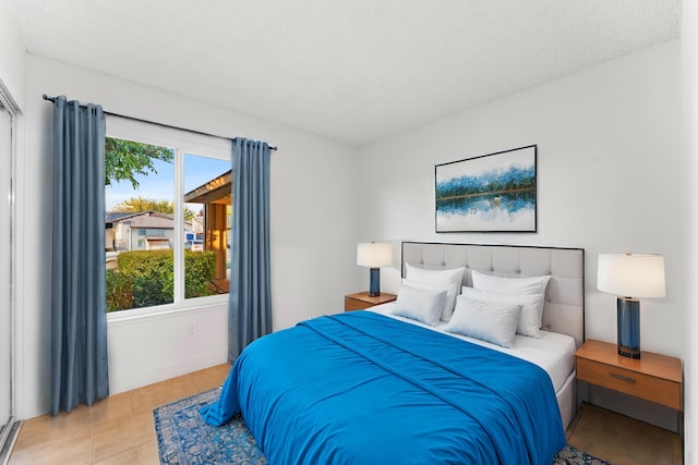 bedroom featuring multiple windows, light tile patterned floors, and a textured ceiling