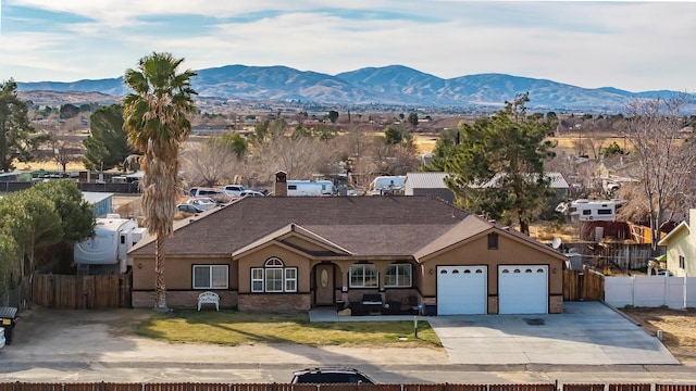 view of front of property with fence, a mountain view, a front lawn, and stucco siding