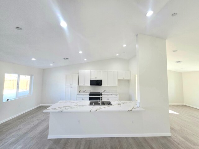 kitchen with lofted ceiling, sink, gray cabinetry, stainless steel appliances, and a kitchen island with sink