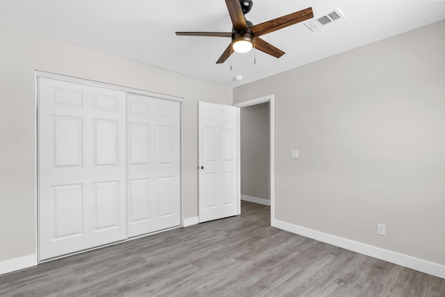 unfurnished bedroom featuring ceiling fan, a closet, and light wood-type flooring