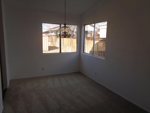 unfurnished dining area with a chandelier, dark colored carpet, lofted ceiling, and baseboards