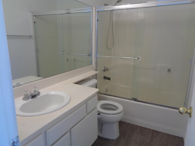 full bathroom featuring toilet, shower / bath combination with glass door, wood finished floors, and vanity