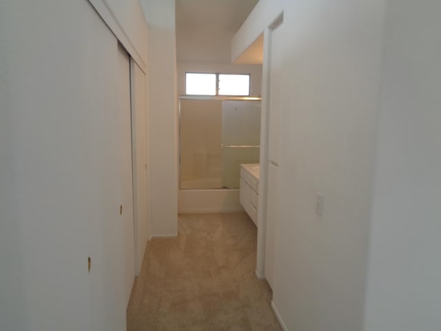 hallway featuring light colored carpet