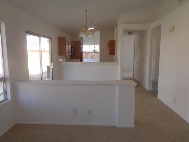 kitchen featuring a peninsula, light countertops, a wealth of natural light, and light colored carpet