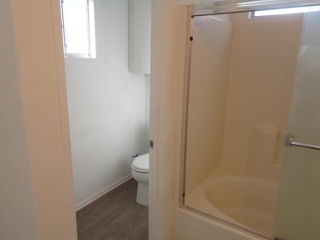 full bathroom featuring toilet, baseboards, combined bath / shower with glass door, and wood finished floors