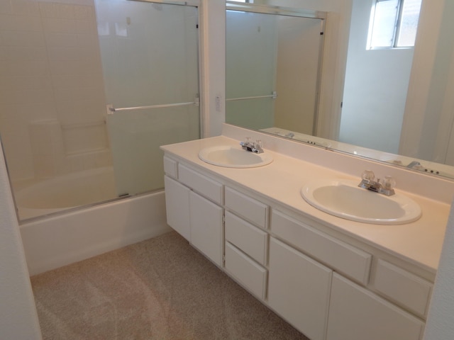 bathroom featuring double vanity, combined bath / shower with glass door, and a sink