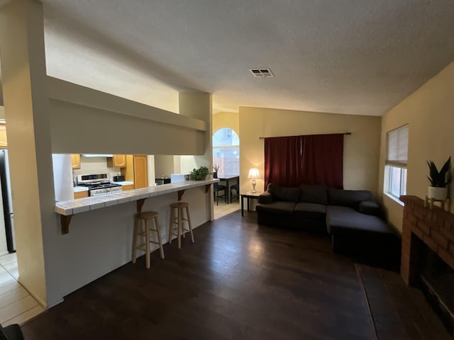 living area featuring lofted ceiling, a wealth of natural light, visible vents, and dark wood finished floors