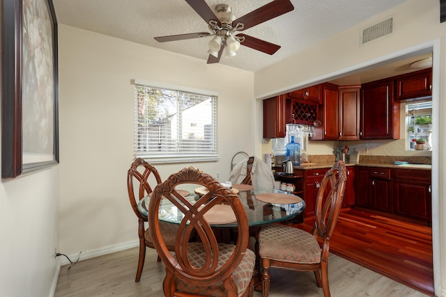 dining area with a healthy amount of sunlight, a textured ceiling, and light wood-type flooring