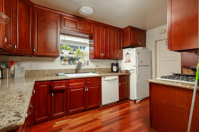 kitchen featuring sink, white appliances, light hardwood / wood-style flooring, backsplash, and light stone countertops