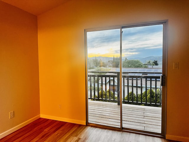 empty room with a mountain view, wood finished floors, and baseboards