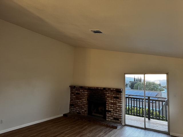 unfurnished living room with wood finished floors, baseboards, a brick fireplace, and vaulted ceiling