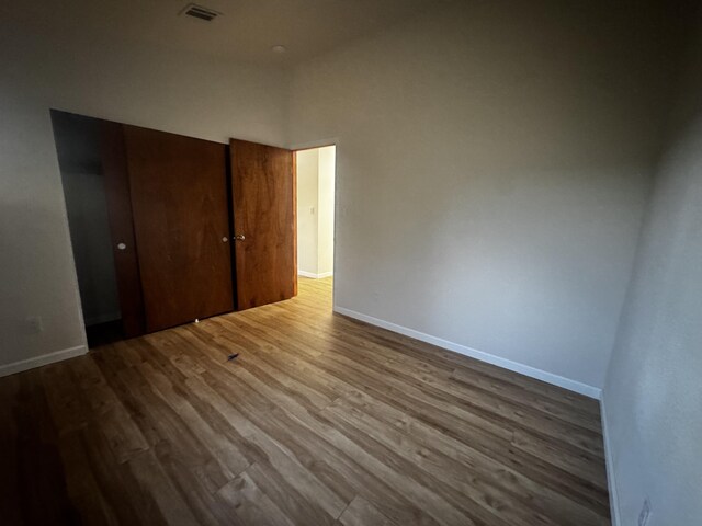 unfurnished bedroom with baseboards, wood finished floors, and a closet