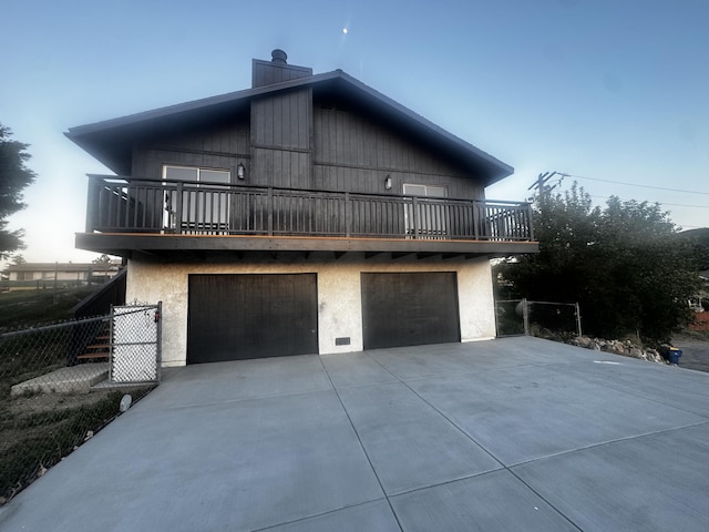 42821 Apollo Pl, Lake Hughes, CA 93532 - view of home's exterior with a balcony, driveway, a chimney, an attached garage, and stucco siding