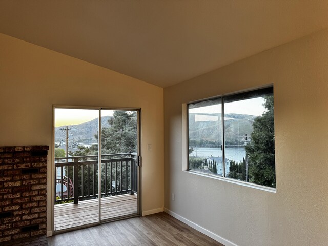 empty room with wood finished floors, baseboards, vaulted ceiling, and a mountain view
