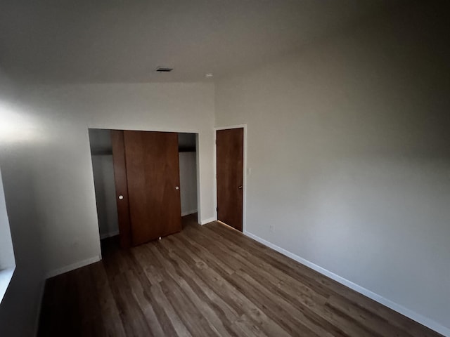 unfurnished bedroom with dark wood finished floors, baseboards, and a closet