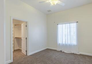 unfurnished bedroom with ceiling fan, a spacious closet, multiple windows, and a closet