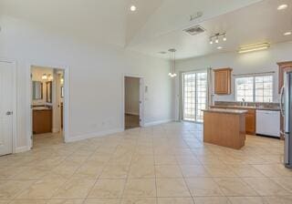 kitchen featuring white dishwasher, light tile patterned floors, decorative light fixtures, a center island, and stainless steel refrigerator