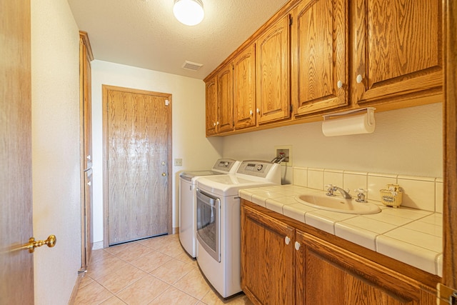 laundry room featuring cabinets, sink, separate washer and dryer, a textured ceiling, and light tile patterned floors