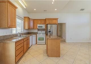 kitchen with stainless steel refrigerator with ice dispenser, sink, light tile patterned floors, range, and a kitchen island