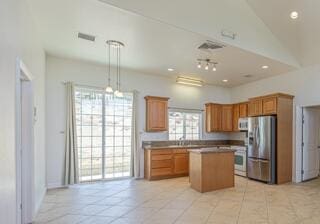 kitchen featuring stainless steel refrigerator, a high ceiling, light tile patterned floors, pendant lighting, and a kitchen island