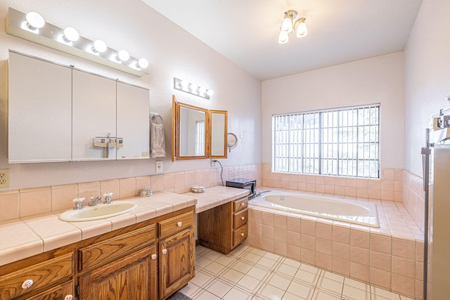 bathroom with tile patterned floors, tiled bath, and vanity