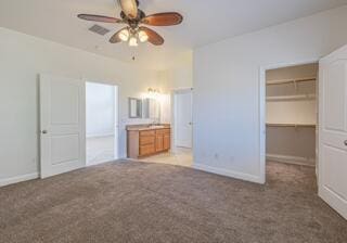 unfurnished bedroom featuring carpet flooring, a walk in closet, ceiling fan, and a closet