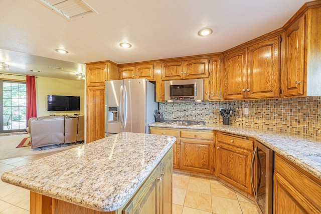 kitchen featuring decorative backsplash, a center island, light stone counters, and appliances with stainless steel finishes