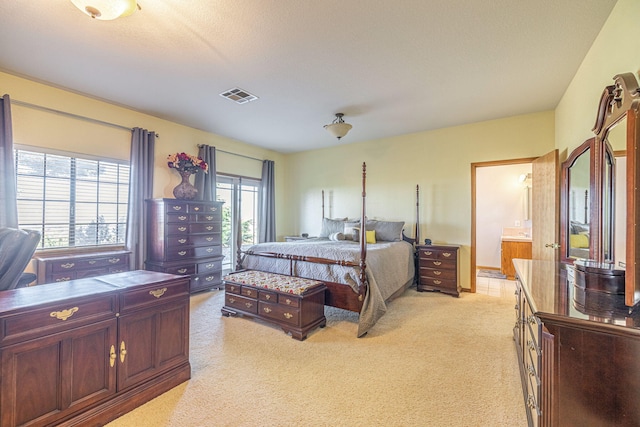 bedroom featuring a textured ceiling, light colored carpet, multiple windows, and ensuite bath