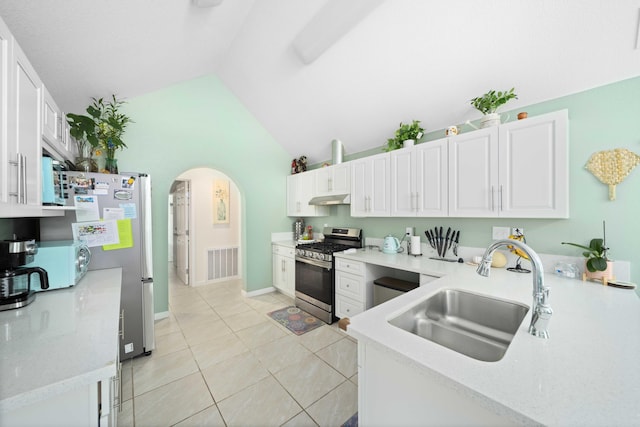 kitchen with sink, vaulted ceiling, light tile patterned floors, appliances with stainless steel finishes, and white cabinetry