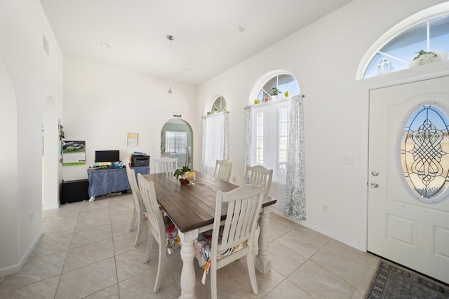 tiled dining space with a towering ceiling and plenty of natural light