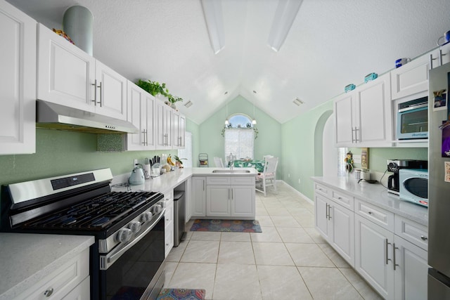 kitchen featuring lofted ceiling, white cabinets, stainless steel gas range, light tile patterned floors, and kitchen peninsula