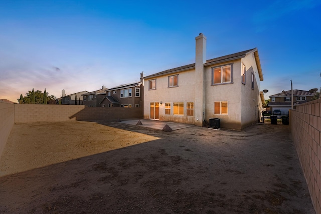 back of property with stucco siding, cooling unit, a chimney, a fenced backyard, and a patio area